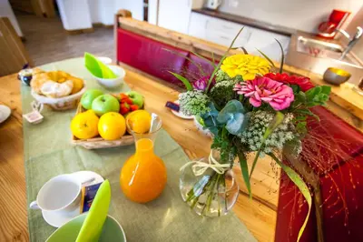 a table with a vase filled with flowers and fruit at Alpine Mountain Chalet in San Vigilio Di Marebbe