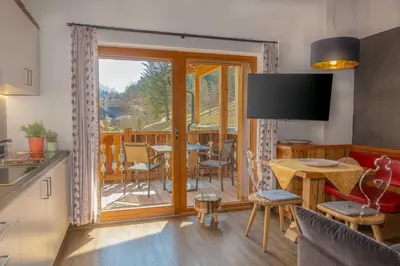 a kitchen and living room with a view of a deck at Alpine Mountain Chalet in San Vigilio Di Marebbe