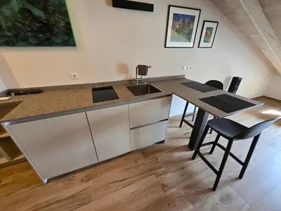 a kitchen with a counter with a sink and chairs at Sweet Piccolino in Merano
