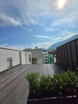 a balcony with a wooden deck with mountains in the background at Sweet Piccolino in Merano