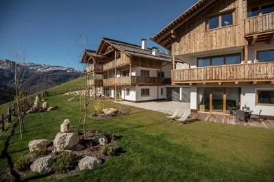 a kitchen with wooden ceilings and a table with chairs at Appartements Chalet Bandiarac in San Cassiano