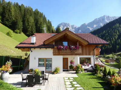 a house in the mountains with a table and chairs at Lüch da Mirió in La Valle