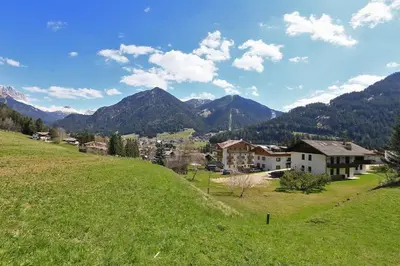 a green field with houses and mountains in the background at Nel cuore delle Dolomiti fino a 8 persone in Vigo di Fassa