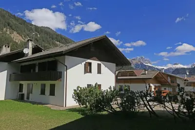 a white house with mountains in the background at Nel cuore delle Dolomiti fino a 8 persone in Vigo di Fassa