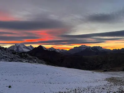 a sunset over a snowy mountain range with mountains at Casa di Charme sul Civetta Dolomiti in Caprile