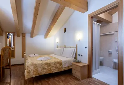 a bedroom with a bed and a bathroom at Hotel Sella Ronda Serenella - A 50 mt dalle piste da sci in Campitello di Fassa