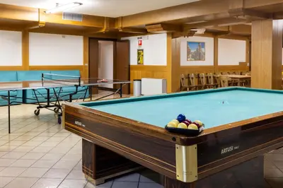 a pool table in a room with two tables at Hotel Sella Ronda Serenella - A 50 mt dalle piste da sci in Campitello di Fassa