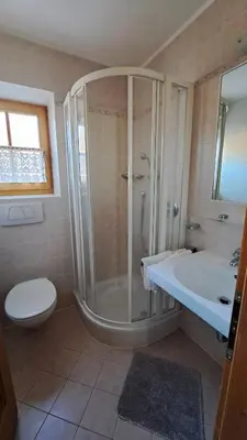 a bathroom with a shower and a toilet and a sink at Haus am Park in Rasùn di Sotto
