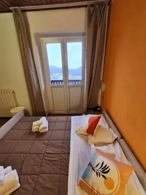 a bedroom with two beds and a window at Excelsior Hotel Cimone LowCost in San Martino di Castrozza