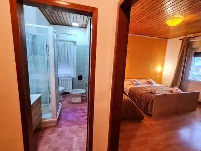 a bedroom with a bed and a bathroom with a shower at Excelsior Hotel Cimone LowCost in San Martino di Castrozza