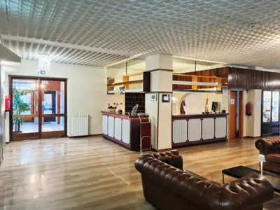 a living room with a couch and a kitchen at Excelsior Hotel Cimone LowCost in San Martino di Castrozza