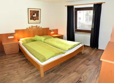 a bedroom with a bed with green sheets and a window at Apartments Rezia in Ortisei