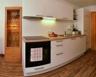 a kitchen with white cabinets and a black oven at Apartments Rezia in Ortisei