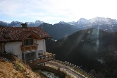 a house on a hill with mountains in the background at Lüch da Börz in Antermoia