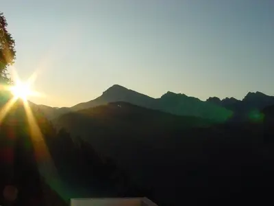 a sunset over a mountain with the sun shining on it at Lüch da Börz in Antermoia