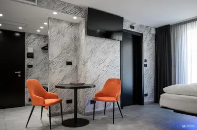 a bedroom with orange chairs and a table and a bed at ADV HOME - Exclusive Rooms in Bolzano