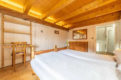 a bedroom with a white bed and a wooden ceiling at La Casa dei Botiri in Rocca Pietore
