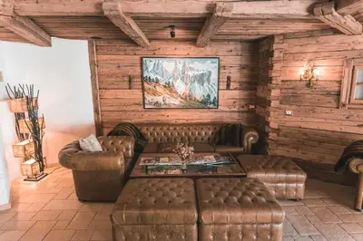 a living room with leather couches and a table at Dorfhotel Beludei in Santa Cristina in Val Gardena