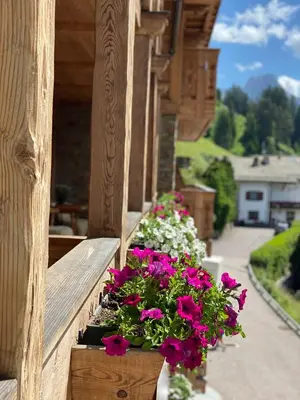a balcony with flowers on the ledge of a building at Dorfhotel Beludei in Santa Cristina in Val Gardena