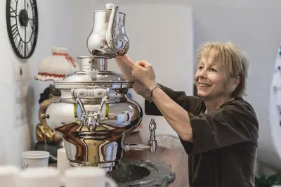 a woman is standing next to a machine at Dorfhotel Beludei in Santa Cristina in Val Gardena