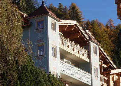a blue building with a balcony on the side of it at Dorfhotel Beludei in Santa Cristina in Val Gardena