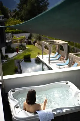 a woman sitting in a bathtub in a backyard at Chalet Merangardenvilla in Merano