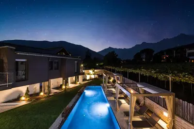 a backyard with a swimming pool at night at Chalet Merangardenvilla in Merano