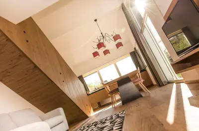 a living room with wooden floors and a large window at Chalet Merangardenvilla in Merano