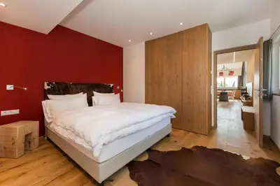 a bedroom with a large bed and a red wall at Chalet Merangardenvilla in Merano