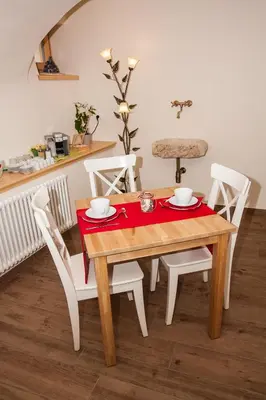 a wooden table with white chairs and a red napkin on it at B&B Incanto in Cles
