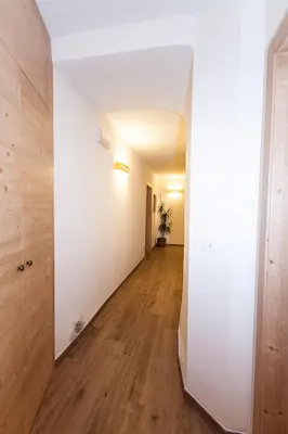 an empty hallway with white walls and wood floors at B&B Incanto in Cles