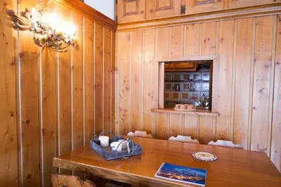 a dining room with wooden walls and a wooden table at Verocai Studio by WelcHome in Cortina dʼAmpezzo