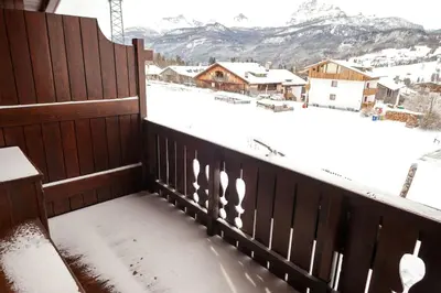 a balcony with snow on the roof of a house at Verocai Views by WelcHome in Cortina dʼAmpezzo