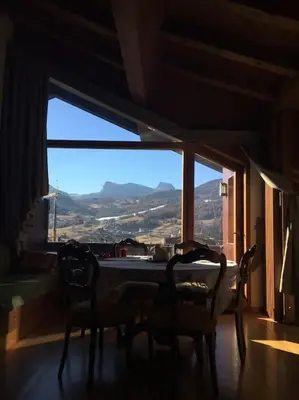 a dining room with a table and chairs and a large window at Verocai Views by WelcHome in Cortina dʼAmpezzo