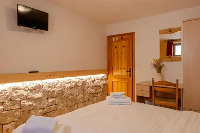a bedroom with a bed and a stone wall at Villa Maria in Falcade