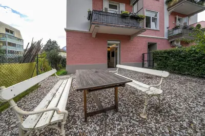 a picnic table and benches in front of a pink building at Apartment Heinz in Merano
