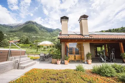 a house with a patio with mountains in the background at Apartment Egghof im Weingut in Merano