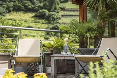 two chairs and a table on a deck with a view at Apartment Egghof im Weingut in Merano