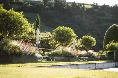 a park with two benches and flowers and trees at Apartment Egghof im Weingut in Merano