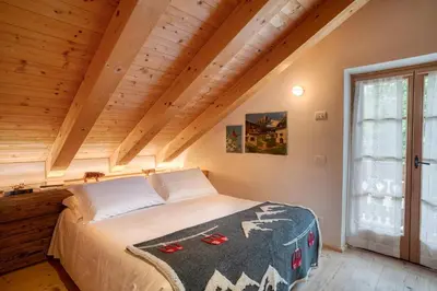 a bedroom with a bed in a room with wooden ceilings at Cà Bianca delle Dolomiti in Cortina dʼAmpezzo