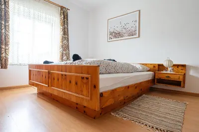 a bedroom with a wooden bed and a window at Stampferhof - Agriturismo in Racines