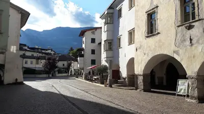 an empty street in a town with mountains in the background at mama's room in Egna