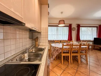 a kitchen with a sink and a table with chairs at Appartamento Al Ruscello in Canazei
