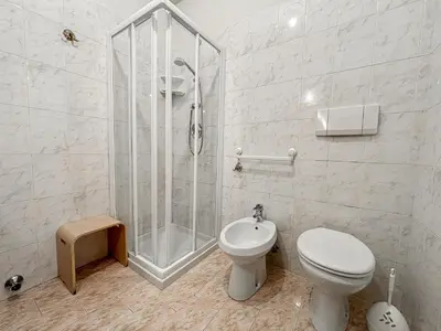 a white bathroom with a shower and a toilet at Appartamento Al Ruscello in Canazei