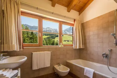 a bathroom with a tub and a sink and a window at Appartamenti Les Viles in La Villa