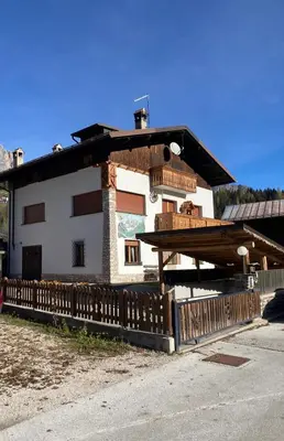 a building with a wooden fence in front of it at Appartamento Canes in Falcade