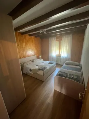 a bedroom with two beds and a window in it at Appartamento Canes in Falcade