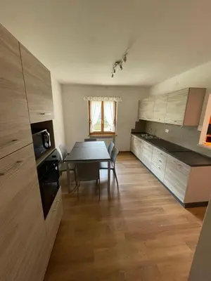 a kitchen with a table and a dining room at Appartamento Canes in Falcade