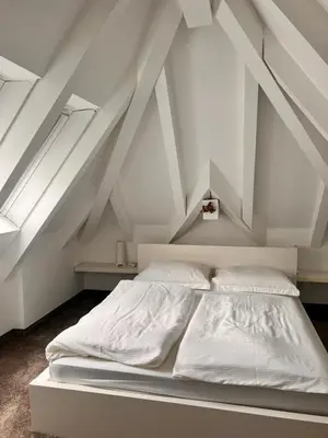 a white bed in a room with a roof at Penthousetraum im Herzen Merans in Merano