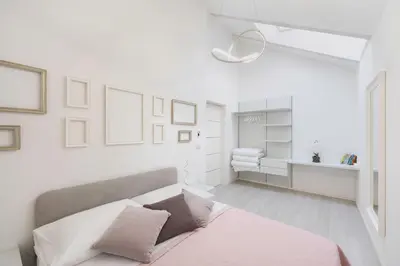 a bedroom with white walls and a bed with pink sheets at Sweethome Gries - Con Garage in Bolzano